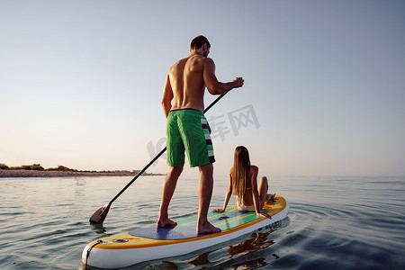 一对年轻男女游客在海上玩桨板
