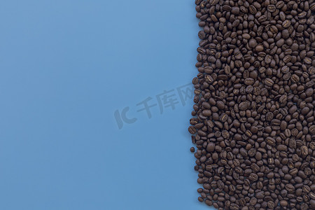 顶视图棕色烤咖啡豆散落在蓝色背景上。