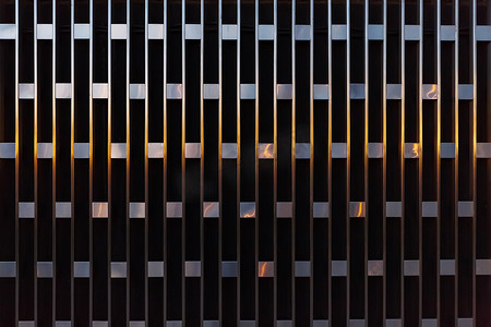 日落时垂直线与金属方块的抽象建筑细节。