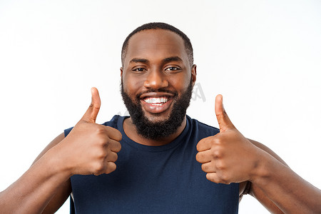 年轻的非洲裔美国男子在孤立的背景下穿着运动服，面带微笑，脸上竖起大拇指。