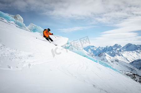 冰川运动摄影照片_阳光明媚的日子里，专业滑雪者在冰川和高雪山的背景下，在雪坡上快速滑行。