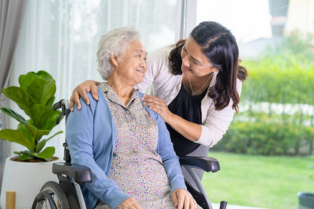 护理人员的女儿帮助坐在轮椅上的亚洲老人或老年老太太。