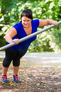 肥胖妇女在公园户外做运动伸展运动