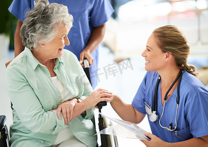 一位漂亮的女护士在医院与坐在轮椅上的老年患者讨论治疗方法的镜头