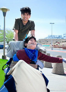 黑道大哥摄影照片_大哥推着轮椅上快乐的残疾男孩