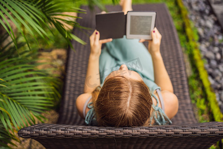 女人在花园的躺椅上看电子书