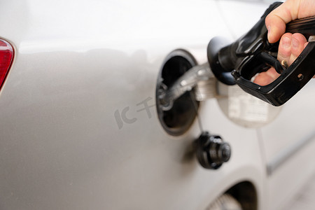 上涨摄影照片_由于燃油成本上涨，一名男子在加油站特写向汽车油箱加注柴油