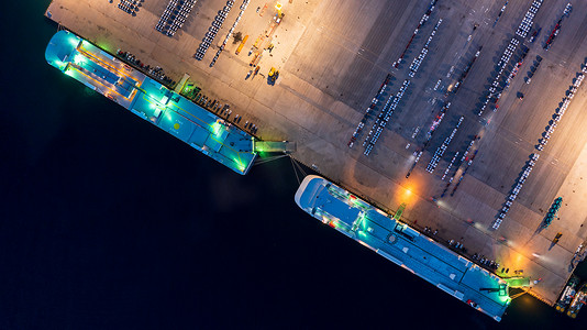 新车在世界各地的进口出口港口排队，汽车和汽车滚装船码头，鸟瞰一排排新车在夜间等待调度和装运。