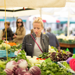 买水果摄影照片_妇女在当地食品市场购买蔬菜。