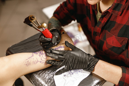 纹身大师手戴手套拿着纹身机的特写照片