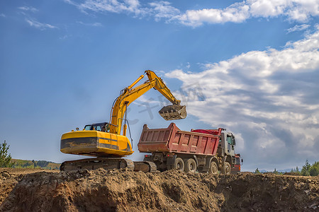 挖掘机摄影照片_在建筑工地工作的黄色挖掘机和空自卸车