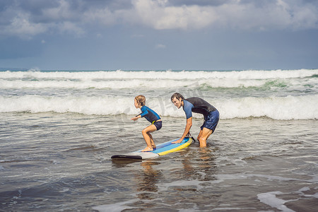 父亲或教练教他 5 岁的儿子如何在假期或假期在海上冲浪。