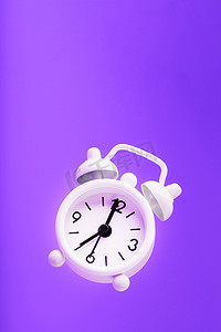上午摄影照片_白色复古风格闹钟在紫色背景上隔离的悬浮状态。