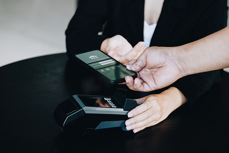 消费卡摄影照片_支付安全技术概念和服务费，员工持有电子卡机，供客户使用智能手机通过 paywave 技术进行支付。