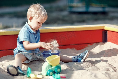 玩沙子摄影照片_小男孩在沙箱里玩沙玩具