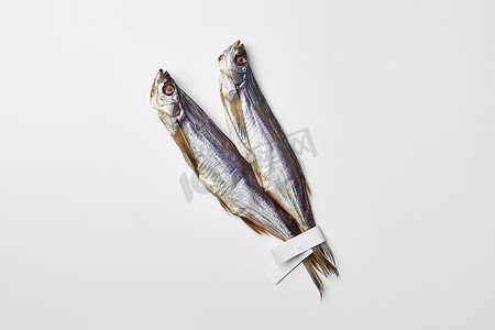 两条咸风干剑鱼，尾巴上有纸标签，隔离在白色