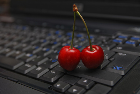 红状摄影照片_笔记本电脑键盘上的新鲜樱桃