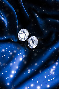 深蓝色丝绸上的奢华钻石耳环，雪光闪闪，节日冬季魔法珠宝礼物