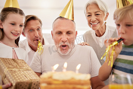 老人在家里与家人一起庆祝生日，戴着派对帽，吹着口哨。