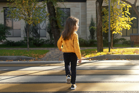 一个小女孩在斑马线上过马路，环顾四周