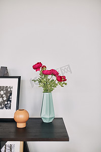 红色的花站在桌子上的蓝色花瓶里。内部细节。
