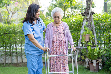 医生帮助和护理亚洲老年或老年老妇妇女在快乐的新鲜假期在公园散步时使用健康状况良好的助行器。