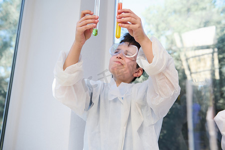 专注于在化学课上做实验的男学生手中装有彩色试剂和化学品的试管