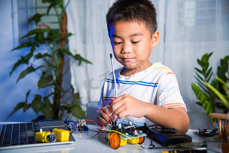 亚洲男孩用 Arduino 机器人汽车将能量和信号电缆插入传感器芯片