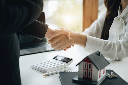担保、抵押、签约、保险、合同、协议概念，房地产经纪人在达成交易后与客户握手祝贺他们