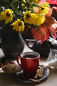 一杯茶，一束秋花和彩叶，秋天的早晨概念。