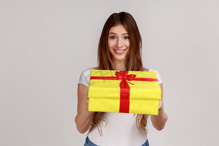 微笑的黑发女人的肖像，送上黄色包装的礼盒，祝贺节日
