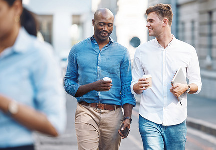 行走男摄影照片_男人们，一边散步一边喝着外卖咖啡，一边聊天一边微笑，在午休时间放松身心。
