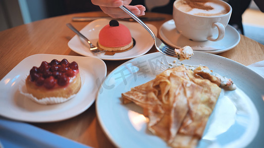 一桌点心摄影照片_女孩早餐时的一桌蛋糕和咖啡。
