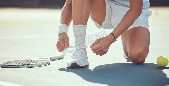 网球摄影照片_网球运动员系鞋，为网球场上的运动、健身或比赛训练做准备。