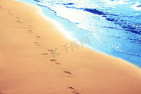 走在沙滩上，沙滩上留下脚印。