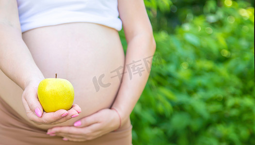孕妇手里拿着一个苹果。