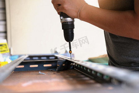自己动手的概念，工匠使用电钻组装旧铁件。