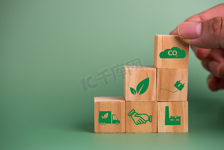 能量方块摄影照片_手持木立方块图标二氧化碳碳信用额和生态能源绿色技术在绿色背景下。