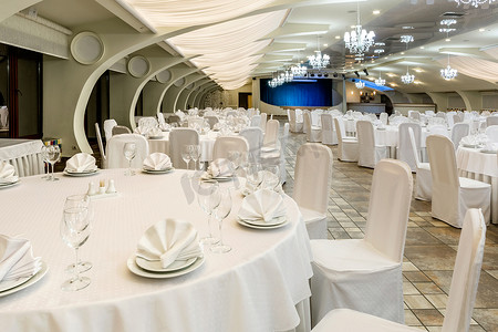 宴会厅以白色装饰，配有圆桌和表演舞台