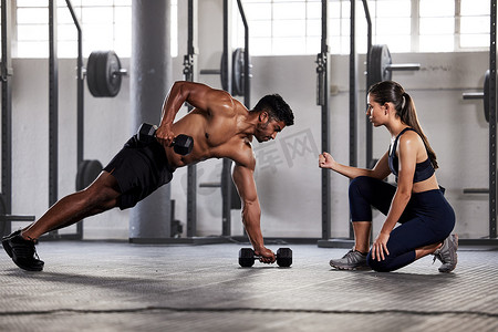 肌肉发达的运动员与女健身教练或健身教练一起进行健身锻炼、推力板练习。