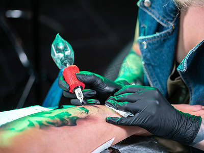 纹身艺术家的特写镜头展示了用油漆获得黑色头骨纹身的过程。
