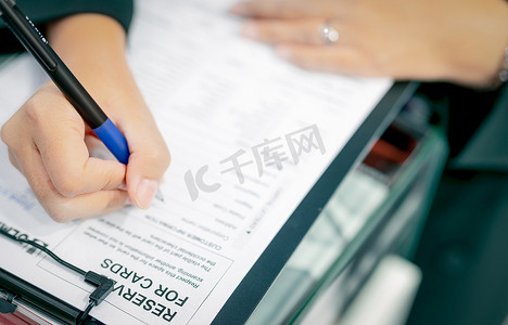 商务人员手持笔，以纸质形式填写公司简介以签订合同协议，并完成交易。
