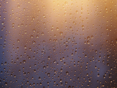水和雨滴在玻璃上的复古色调，抽象视图，蓝色玻璃背景上的雨滴在雨后滴在玻璃上。