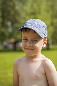 一个可爱的金发男孩坐在多汁的草地上，体验着夏日在河边散步的乐趣。