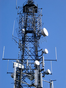 塔信号摄影照片_钢格通信塔的低角度视图，带有一系列用于传输和接收的碟形天线
