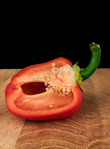 红木板摄影照片_一块成熟的胡椒，红甜的，在黑色背景的木板上