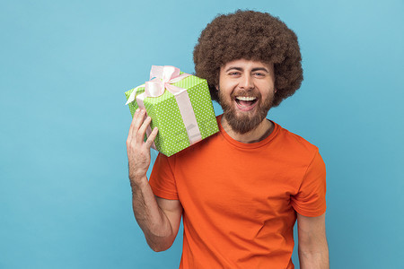 绿色购物节摄影照片_快乐的男人拿着绿色礼物盒，带着快乐的表情看着相机。