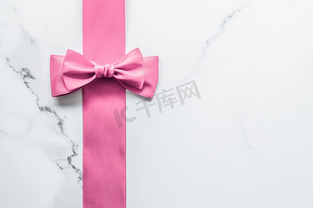 大理石背景上的粉色丝带和蝴蝶结、女婴送礼会礼物和豪华美容品牌的魅力时尚礼品装饰、假日平铺设计