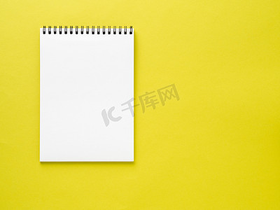 黄色书桌上的空白记事本白页，彩色背景。