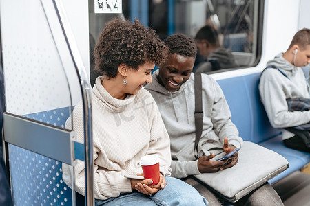 年轻夫妇坐在地铁车厢里使用智能手机。